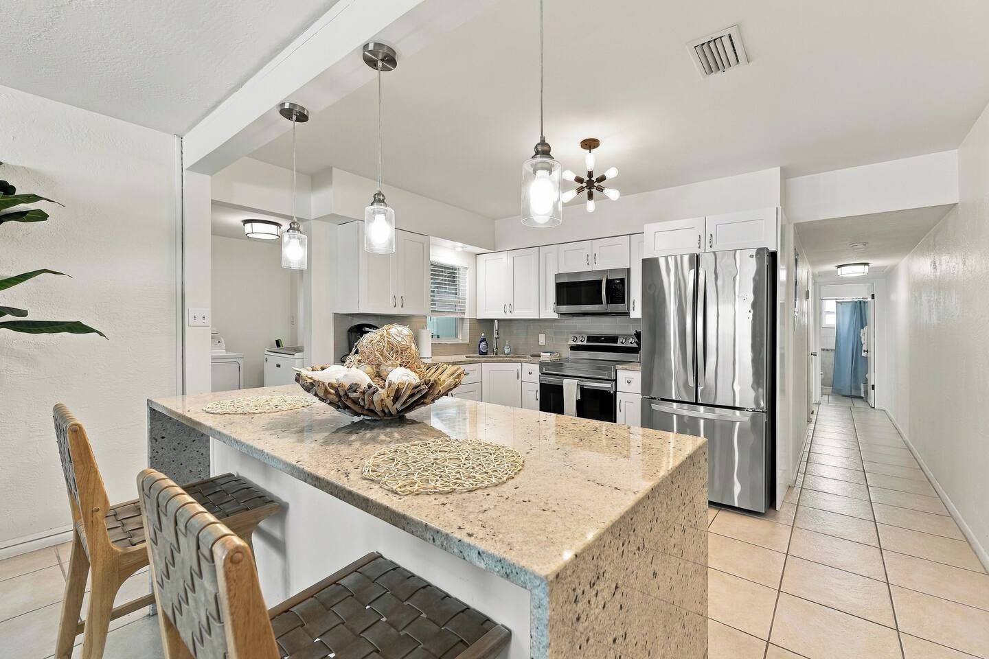 A modern kitchen with a central island, stainless steel appliances, and pendant lighting.