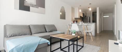 A modern living room with a sofa, coffee table, and dining area with chairs.