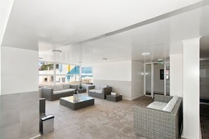Een moderne lobby met rieten meubels, een glazen salontafel en uitzicht op het exterieur.