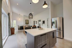 A modern kitchen with a large island, stainless steel appliances, and pendant lighting.