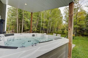 A hot tub with a wooden deck and a view of a forested area.