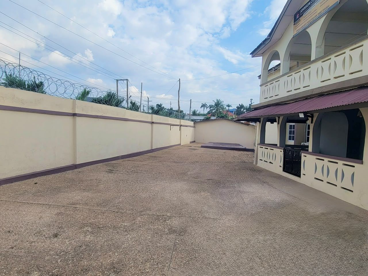 A building with a covered outdoor area, a balcony, and a gated entrance.