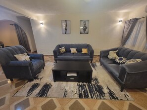 A living room with a sofa set, a coffee table, and a patterned rug.