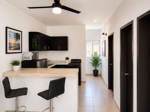 A modern kitchen with black cabinets, a microwave, a stove, and two bar stools. - Cozy apartment Independencia condo with AC in vibrant Puerto Vallarta (Puerto Vallarta)