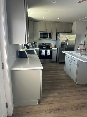 A modern kitchen with stainless steel appliances, a microwave, and a refrigerator.