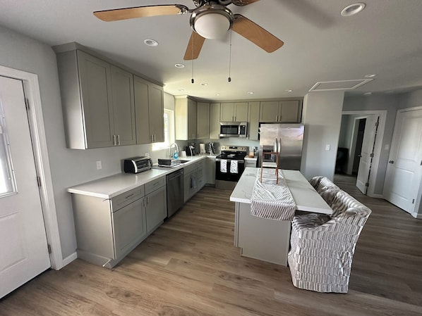 A modern kitchen with a central island, built-in appliances, and a ceiling fan.