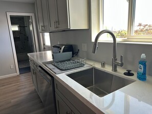 A modern kitchen with stainless steel appliances, a double sink, and a window providing natural light.