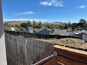 A residential area with houses, a wooden fence, and a hilly landscape in the background.