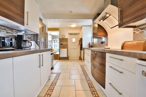 A modern kitchen with white cabinetry, a coffee machine, and a microwave. - The Swansea Homestay | Spacious 4-Bed Retreat (Swansea)