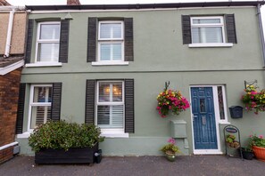A two-story house with a blue door, shutters, and flower baskets. - The Swansea Homestay | Spacious 4-Bed Retreat (Swansea)