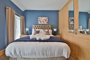 Ein Schlafzimmer mit einem großen Bett, einem Kopfteil, einem Kleiderschrank und einem Gemälde an der Wand.