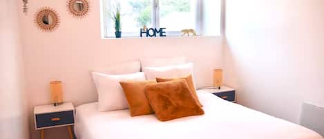 A bedroom with a bed, two bedside tables, a window, and wall decorations.