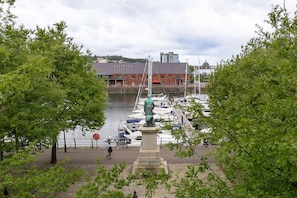 A marina with boats docked, a statue in the foreground, and a red building in the background. - Swansea Waterfront 1 Bed Apt with Parking (Swansea)