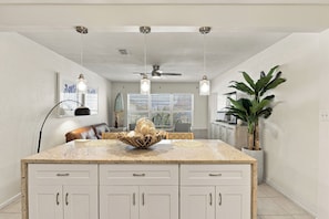 A kitchen with a central island, white cabinetry, pendant lighting, a ceiling fan, and a large potted plant. - Walk to Cocoa Beach + Kids Clubhouse+Private Yard (Cocoa Beach)
