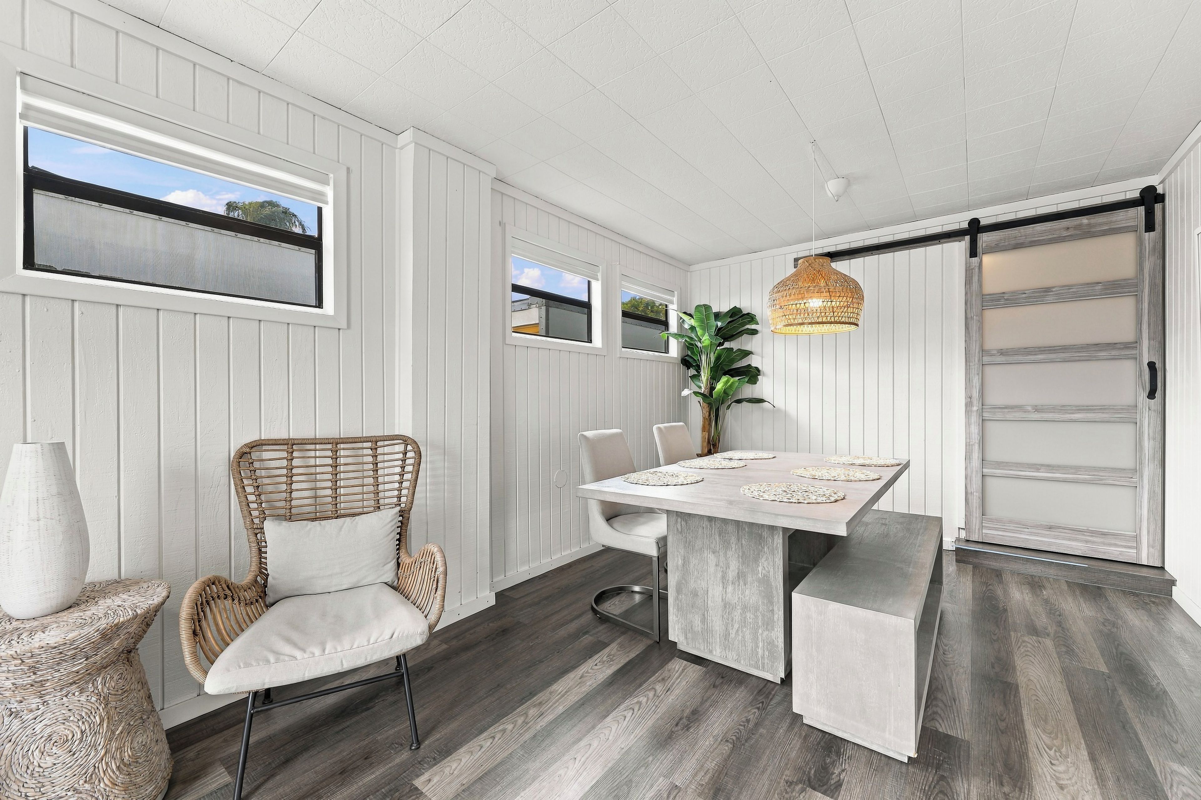 A dining area with a table, chairs, a hanging light fixture, and a sliding door.