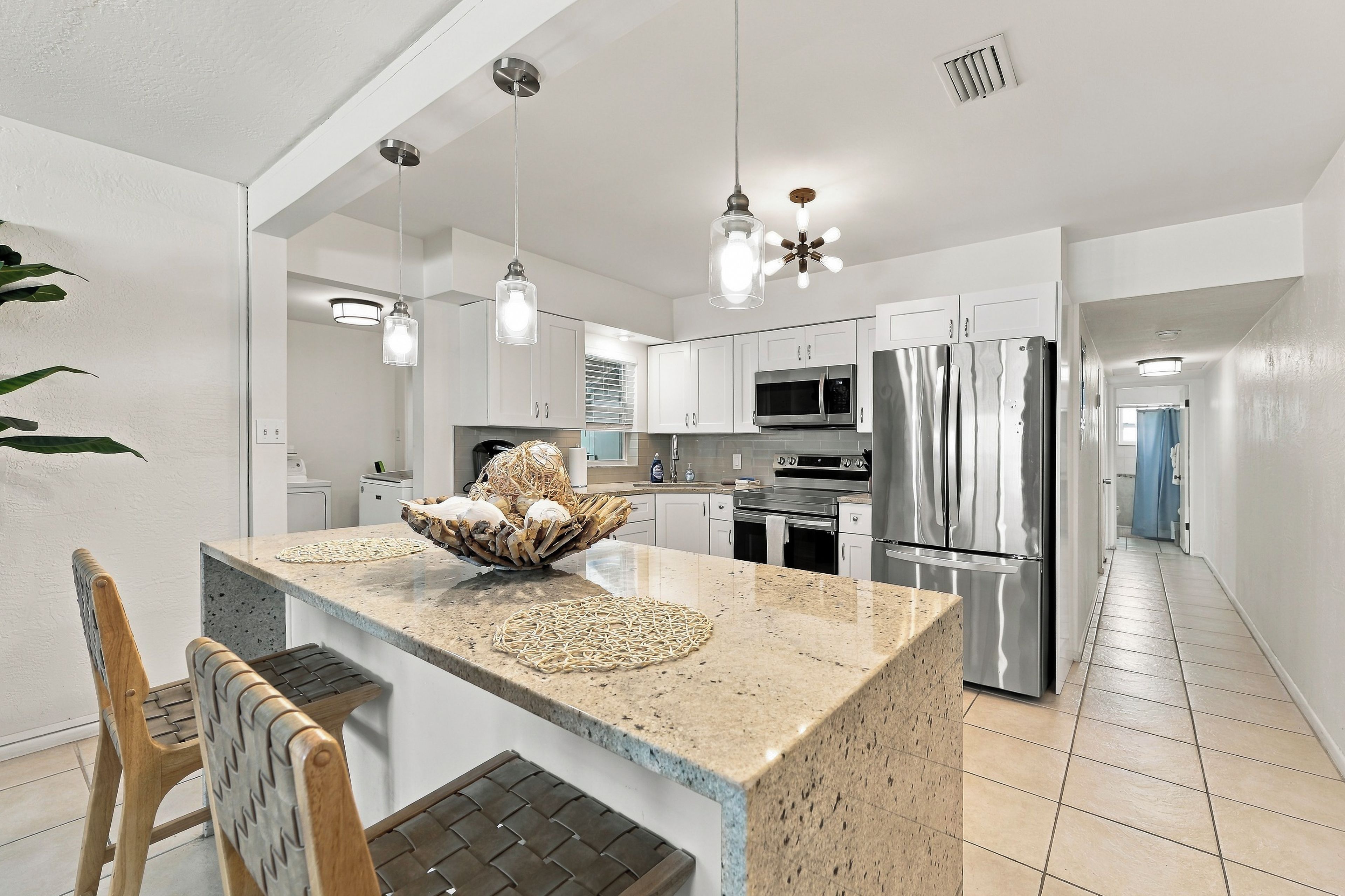 A modern kitchen with a central island, stainless steel appliances, and pendant lighting.