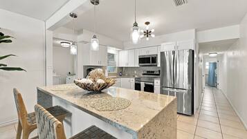 A modern kitchen with a central island, stainless steel appliances, and pendant lighting.