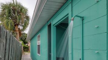 A narrow pathway leading to a teal-colored building with a wooden fence on one side.
