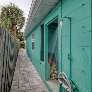 A narrow pathway leading to a teal-colored building with a wooden fence on one side. - Walk to Cocoa Beach + Kids Clubhouse+Private Yard (Cocoa Beach)