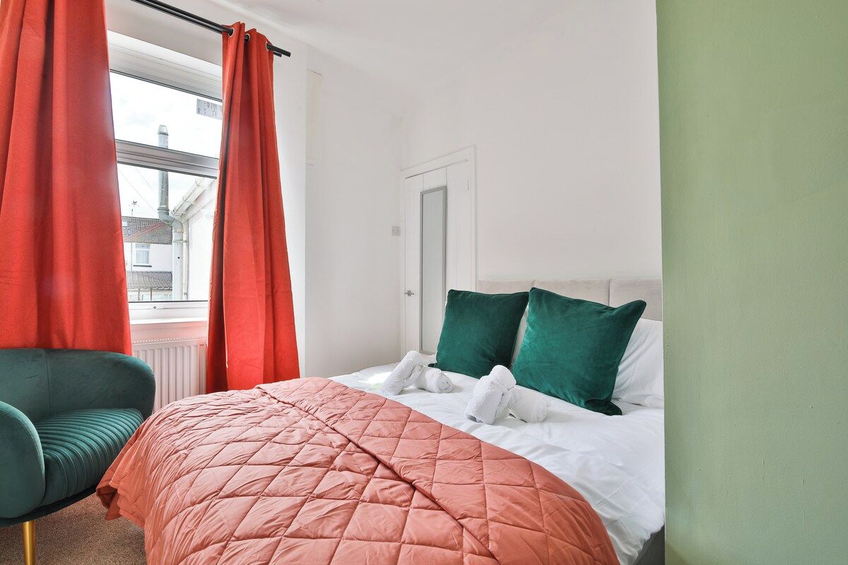 Una habitación de hotel con una cama, una silla verde y cortinas rojas.