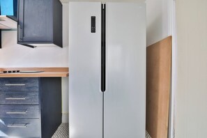 Eine Küche mit einem weißen Kühlschrank, einer Holzauskładung und einem dunklen Schrank.