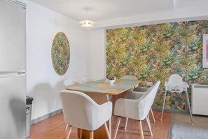 Ein Essbereich mit Tisch, Stühlen, einer Wand mit floralem Muster und einer Deckenleuchte.