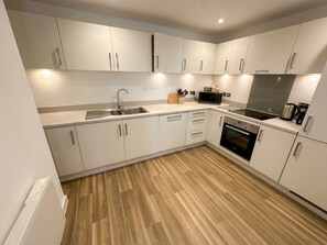 A modern kitchen with white cabinets, a stainless steel sink, and a microwave. - Spacious 2 Bed 2 Bath City Apt with Free Parking (Birmingham)