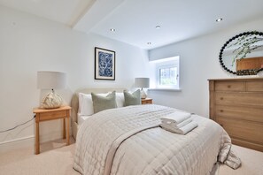 A bedroom with a bed, bedside tables, a dresser, a window, and a wall art piece. - Central 4-Bed Apartment on Mumbles Road (Swansea)