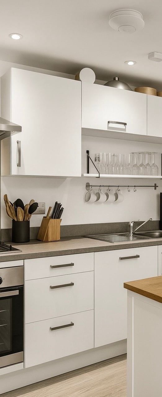 A modern kitchen with white cabinets, a stainless steel sink, and a wooden countertop.