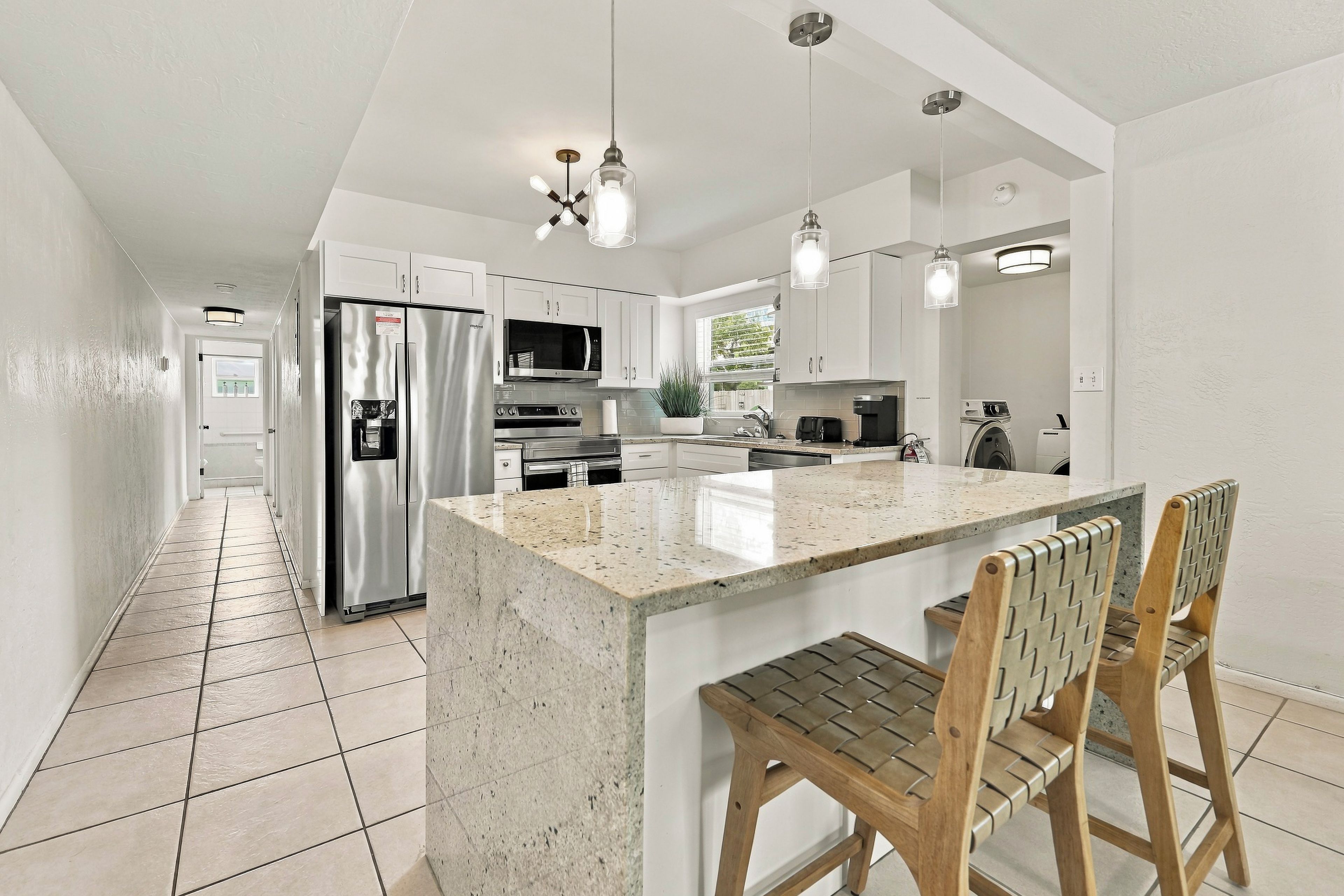 A modern kitchen with a central island, stainless steel appliances, and pendant lighting.