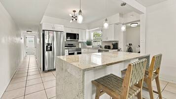 A modern kitchen with a central island, stainless steel appliances, and pendant lighting.