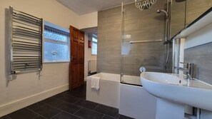 Et moderne badeværelse med badekar, brusebad med glasvægge og en hvid vask.