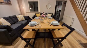 A dining area with a wooden table set for four, surrounded by black chairs. - Swansea City & Bay 4-Bedroom House (Swansea)