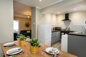 Eine kleine Küche mit Essbereich, Kühlschrank, Herd und Spüle.