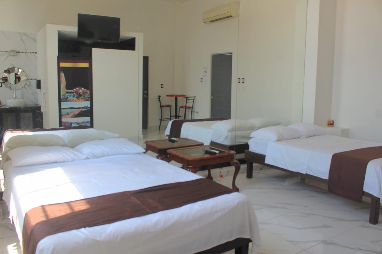 Habitación de hotel con tres camas, un escritorio y una silla.