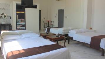 Habitación de hotel con tres camas, un escritorio y una silla.