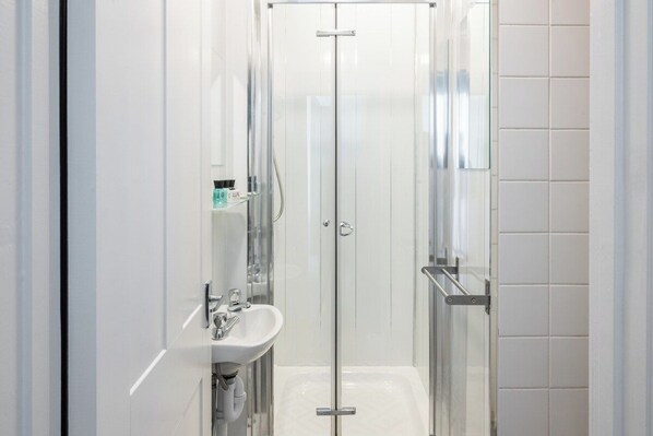 Ein modernes Badezimmer mit Duschkabine aus Glas, einem Waschbecken und einem Spiegel.