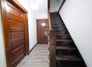 Una escalera de madera con barandilla que conduce a una puerta en la parte superior.