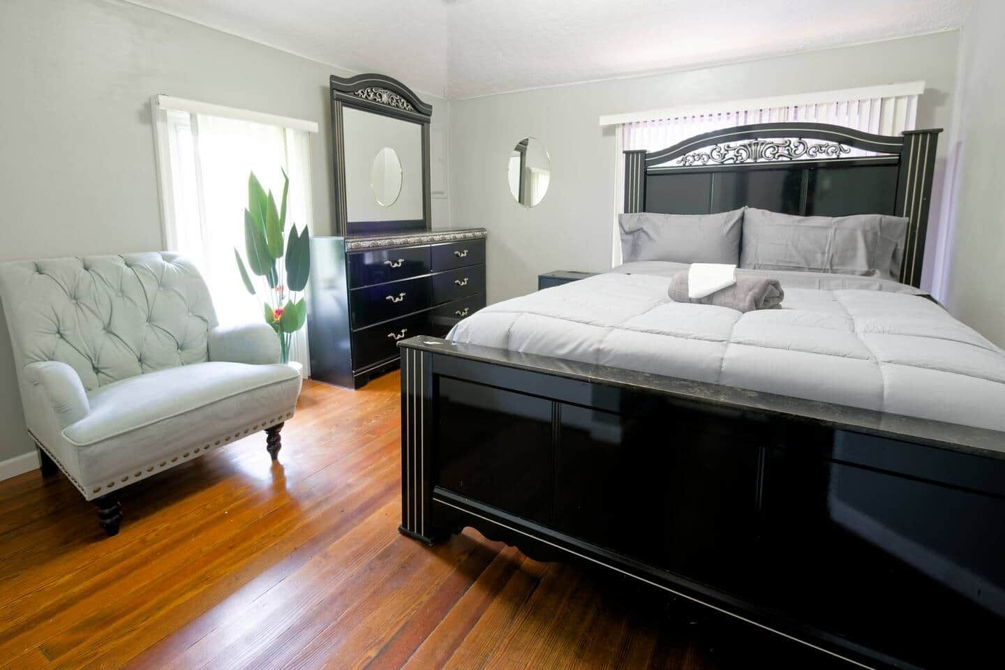 Une chambre à coucher avec un grand lit, une commode, une chaise et un miroir.