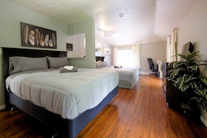 A bedroom with a large bed, a desk, a chair, and a potted plant.