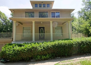 A two-story house with a front porch, a door with an arched window, and a small balcony.