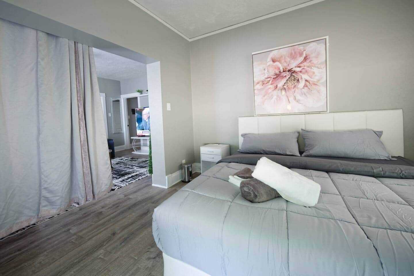 Un dormitorio con una cama grande, una mesita de noche, un televisor y un cuadro en la pared.