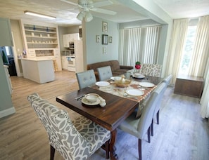 A dining area with a wooden table set for four, surrounded by upholstered chairs.