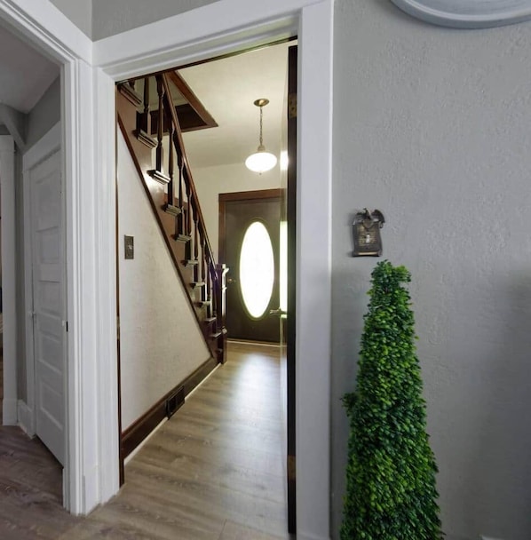 A hallway with a wooden staircase, a door, and a wall-mounted telephone.