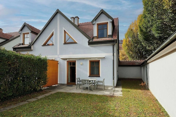 A residential house with a covered patio, a small garden, and a visible garage door.
