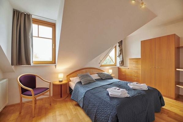 A bedroom with a bed, a chair, a wardrobe, and a window.