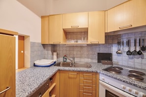 Una cocina con encimeras de granito, armarios de madera, un lavamanos de acero inoxidable y una estufa.