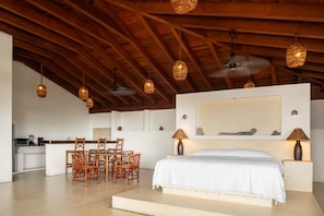 A spacious room with a large bed, a dining area with chairs, and a kitchen area. - Casa Privada Frente al Mar | Lujo, Playa y Exclusi (Troncones)