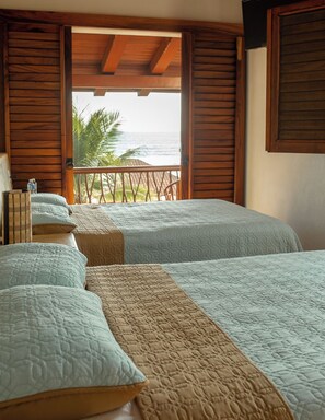 A room with two beds, wooden walls, a balcony with a view of the ocean, and a wooden ceiling. - Casa Privada Frente al Mar | Lujo, Playa y Exclusi (Troncones)