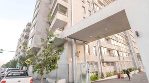 Ein mehrgeschossiges Gebäude mit moderner Architektur, mit Balkonen und einem überdachten Eingang.